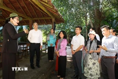 Đồng chí Ngô Đông Hải, Phó Trưởng Ban Tuyên giáo và Dân vận Trung ương (áo trắng, đứng thứ 2 từ trái sang) cùng các đại biểu tham quan nhà phục dựng khu làm việc của các đồng chí lãnh đạo Trung ương Cục miền Nam thời kháng chiến. (Ảnh: Thanh Tân/TTXVN)