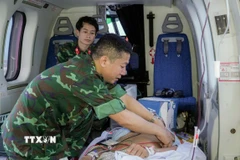 Bác sỹ Tổ Cấp cứu đường không, Bệnh viện Quân y 175 theo dõi, xử trí cho nạn nhân trên trực thăng. (Ảnh: TTXVN phát)