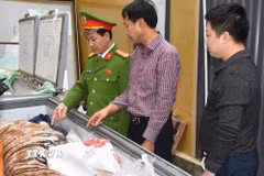 Đối tượng Hoàng Đình Đạt mặc áo kẻ sọc màu đỏ cùng tang vật vụ án. (Ảnh TTXVN phát)