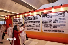 Đại biểu xem Trưng bày ảnh “Dưới cờ Đảng - Đất nước tiến vào Kỷ nguyên mới” do Thông tấn xã Việt Nam thực hiện. (Nguồn: TTXVN)