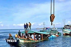 Tàu cá CM 91554 TS bị nạn trên biển được các lực lượng và nhân dân hỗ trợ lai dắt vào bờ. (Ảnh: TTXVN phát)