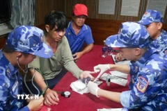 Cán bộ, chiến sỹ tàu cảnh sát biển 4035, Bộ Tư lệnh Vùng Cảnh sát biển 4 chăm sóc, hỗ trợ y tế cho nạn nhân gặp nạn trên biển. (Ảnh: TTXVN phát)