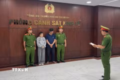 Cơ quan điều tra tống đạt quyết định bắt giữ các đối tượng. (Ảnh: TTXVN phát)