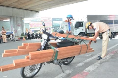 Cảnh sát Giao thông kiểm tra kích thước hàng hóa của một trường hợp vi phạm. (Ảnh: Linh Sơn/TTXVN)