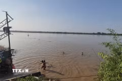 Chỉ vài chục mét sau biển cảnh báo nguy hiểm, nhiều người vẫn vô tư tắm ở bãi tắm tự phát bên bờ sông Hồng, đoạn qua phường Phú Thượng. (Ảnh: Nguyễn Thắng/TTXVN)