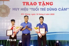 Phó Bí thư Thường trực Tỉnh đoàn Bắc Giang Bùi Văn Hoàng trao tặng Huy hiệu “Tuổi trẻ dũng cảm” cho 2 em là: Phạm Đình Tuấn và Phạm Hoàng Long. (Ảnh: Đồng Thúy/TTXVN)
