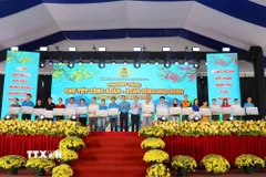 Ông Nguyễn Đình Khang, Chủ tịch Tổng Liên đoàn Lao động Việt Nam và ông Nguyễn Phước Lộc, Phó Bí thư Thành ủy Thành phố Hồ Chí Minh trao tặng vé máy bay cho công nhân lao động về quê đón Tết. (Ảnh: Thanh Vũ/TTXVN)