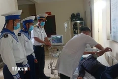 Bác sỹ Bệnh xá đảo Trường Sa kiểm tra sức khỏe bệnh nhân Lê Văn Đông. (Ảnh: TTXVN phát)