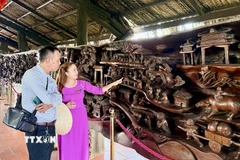 Du khách tham quan bức tranh gỗ lũa khổng lồ dài gần 25m, nặng khoảng 20 tấn, được xem là một trong những tác phẩm công phu bậc nhất Việt Nam. (Ảnh: Thanh Sang/TTXVN)