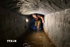 Du khách trải nghiệm đi dưới lòng địa đạo Kỳ Anh có nước ngập. (Ảnh: Đỗ Trưởng/TTXVN)