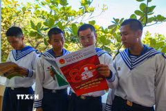 Các chiến sỹ tại đảo Trường Sa Đông đọc báo sau giờ huấn luyện. (Ảnh: Công Luật/ TTXVN)