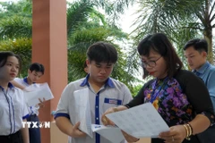 Giám thị tại điểm thi Trường THPT Hòn Đất (Kiên Giang) kiểm tra thông tin thí sinh trước khi vào phòng thi. (Ảnh: Văn Sĩ/TTXVN)