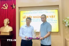 Phó Giám đốc Khu Di tích Chủ tịch Hồ Chí Minh tại Phủ Chủ tịch Nguyễn Văn Dương tiếp nhận lọ hoa do gia đình ông Vũ Thanh Tùng trao tặng. (Ảnh: Phương Lan/TTXVN)