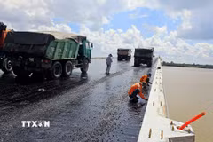Thi công trải thảm nhựa nóng mặt cầu Đại Ngãi 2, ngày 4/5. (Ảnh: Trung Hiếu/TTXVN)