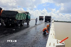 Thi công trải thảm nhựa nóng mặt cầu Đại Ngãi 2, ngày 4/5. (Ảnh: Trung Hiếu/TTXVN)