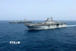 Tàu sân bay USS Abraham Lincoln (phía sau) của hải quân Mỹ di chuyển trên Biển Arab. (Ảnh: AP/TTXVN)