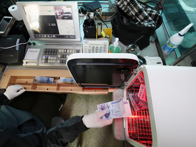 Nhân viên khử trùng tiền giấy nhằm ngăn chặn lây nhiễm COVID-19 tại một nhà ga ở Seoul, Hàn Quốc, ngày 30/3/2020. (Nguồn: THX/TTXVN)