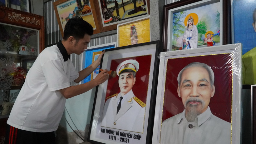 Anh Nguyễn Minh Trí hoàn thiện bức tranh gói vải chân dung Đại tướng Võ Nguyên Giáp. (Ảnh: Văn Sĩ/TTXVN)