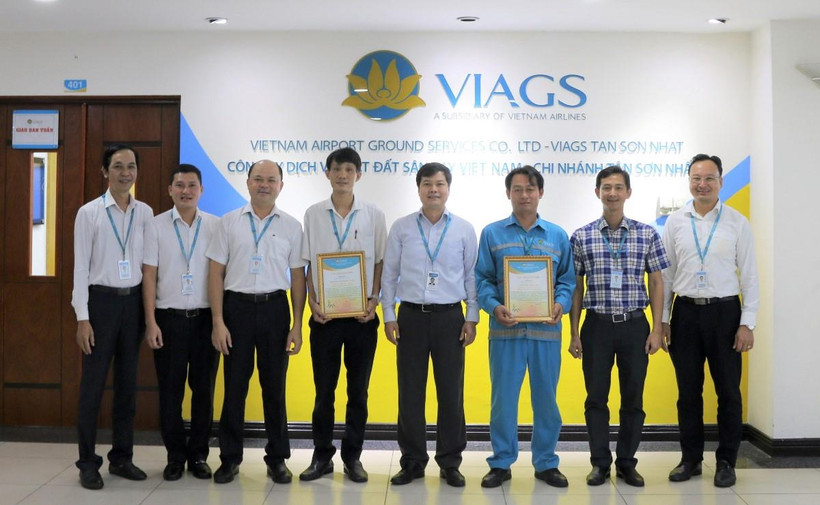 Anh Đường Khánh Tùng (thứ tư từ trái sang) và anh Trần Ngọc Kỳ (thứ ba từ phải sang) nhận thư biểu dương của Ban lãnh đạo Công ty Dịch vụ mặt đất sân bay Việt Nam. (Ảnh: CTV/Vietnam+)