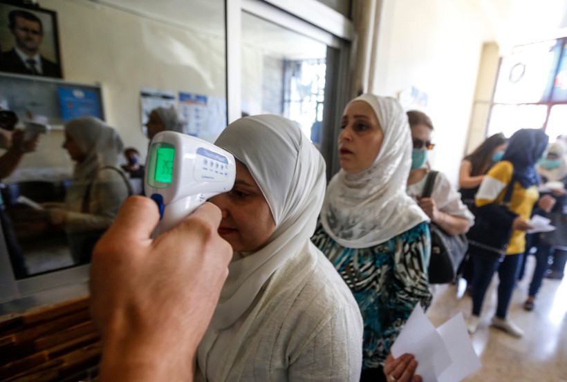 Kiểm tra thân nhiệt phòng lây nhiễm COVID-19 tại một điểm bầu cử ở Damascus, ngày 19/7/2020. (Ảnh: AFP/TTXVN)