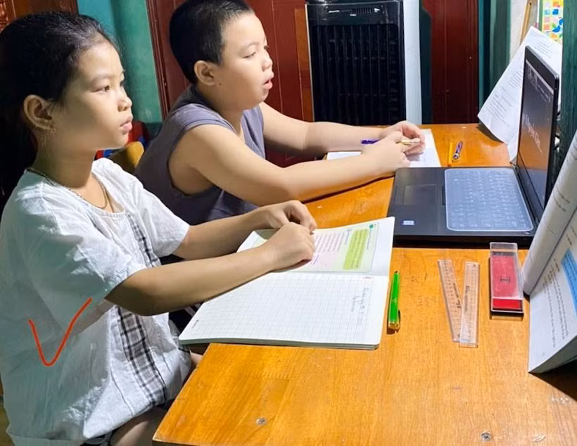 Nhiều trường hợp 2 học sinh phải học chung trên một thiết bị. (Ảnh: TTXVN phát)