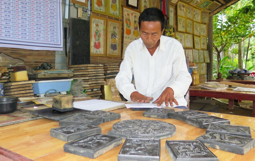 Nghệ nhân Kỳ Hữu Phước in tranh. (Ảnh: Tường Vi/TTXVN)