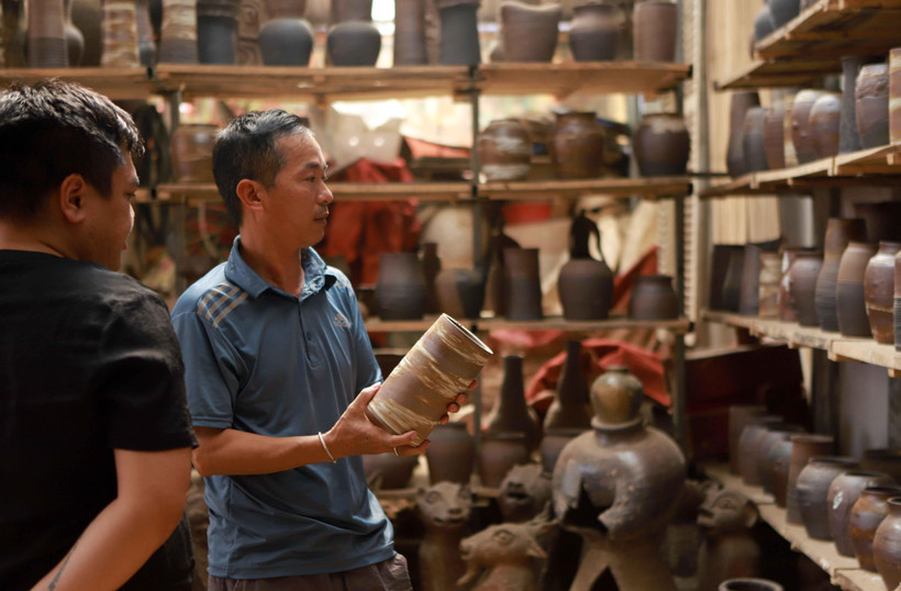 Khách hàng đến xưởng gốm của nghệ nhân Nguyễn Hồng Quang đặt hàng sản phẩm gốm Hương Canh. (Ảnh: Hoàng Hùng/TTXVN)