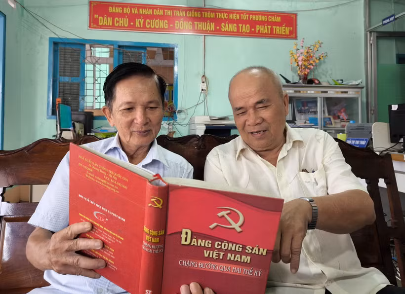 Ông Lê Văn Thiệm (bên trái) tại ấp 6, thị trấn Giồng Trôm (Bến Tre), Đảng viên 35 năm tuổi đảng trao đổi nghiên cứu văn kiện của Đảng với đảng viên trong chi bộ. (Ảnh: Huỳnh Phúc Hậu/TTXVN)
