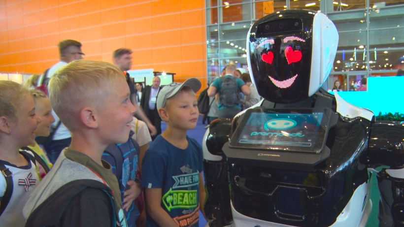 Các em học sinh bên người máy. (Ảnh: Hồng Quân/Vietnam+)