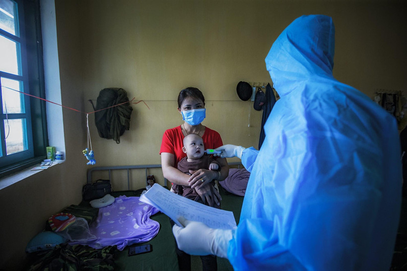 Cán bộ quân y đo thân nhiệt cho một cháu bé đang thực hiện cách ly cùng mẹ tại Trường Quân sự tỉnh Hòa Bình sau khi trở về từ vùng dịch Hàn Quốc. (Ảnh: Trọng Đạt/TTXVN)