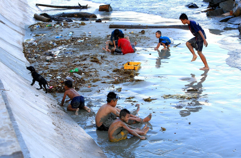 Những đứa trẻ chơi đùa cùng với rác tại bãi tắm gần Cầu Tàu 914. (Ảnh: Ngọc Hà/TTXVN)