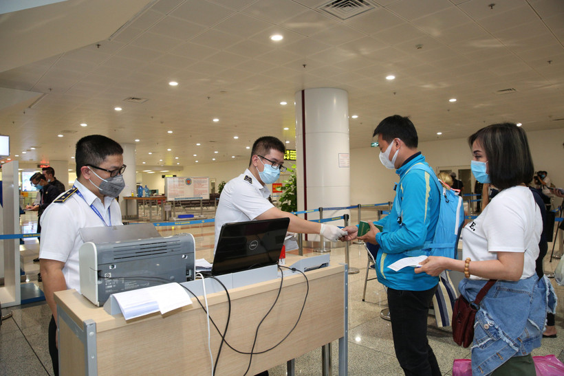 Nhân viên y tế kiểm tra phiếu khai báo y tế của hành khách trước khi làm thủ tục nhập cảnh tại cửa khẩu Sân bay quốc tế Nội Bài (Hà Nội), chiều 7/3. (Ảnh: Dương Giang/TTXVN)