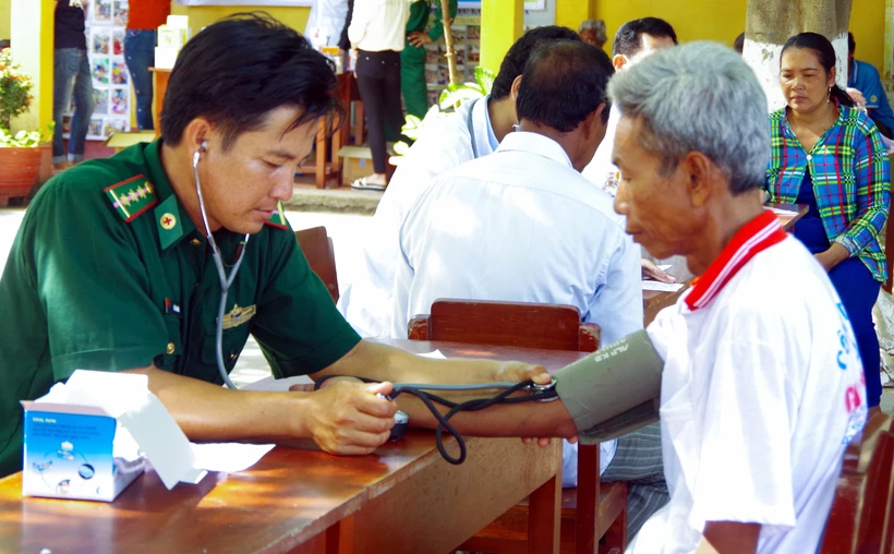 Người “thầy thuốc quân hàm xanh” Lê Văn Quốc khám bệnh cho bà con Khmer nghèo khu vực biên giới biển xã Vĩnh Hải, thị xã Vĩnh Châu, tỉnh Sóc Trăng. (Ảnh: Trung Hiếu-Văn Long/TTXVN)