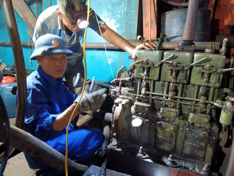 Cán bộ kỹ thuật Âu tàu đảo Sinh Tồn giúp ngư dân sửa chữa máy phát điện của tàu cá QNg 90431 TS. Ảnh: TTXVN phát