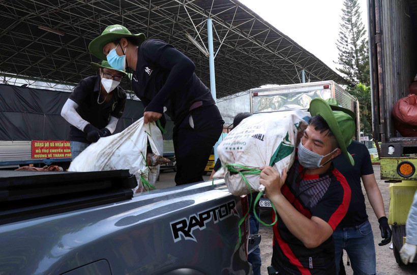 Lực lượng tình nguyện viên, cán bộ Mặt trận bốc xếp hàng hóa do chính quyền, nhân dân Quảng Trị tặng lên các xe vận tải nhỏ chuyển đến các khu tập trung, khu cách ly tại các quận, huyện của Thành phố. (Ảnh: Xuân Khu/TTXVN)