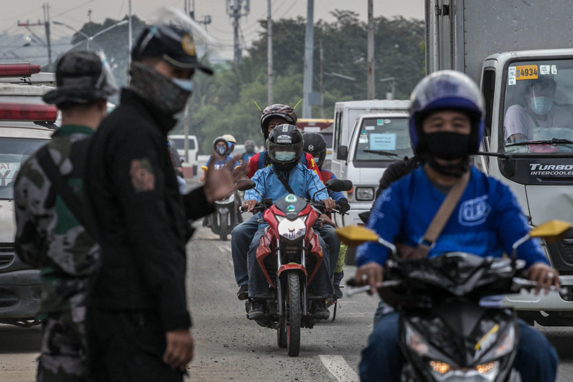 Cảnh sát gác tại một chốt kiểm soát để nhắc nhở người dân thực hiện tốt các biện pháp phòng dịch COVID-19 ở Quezon, ngoại ô Manila, Philippines. (Ảnh: AFP/TTXVN)