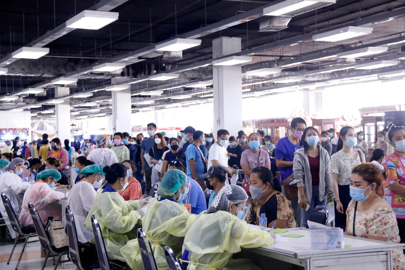 Các nhân viên y tế tại một điểm tiêm ở thủ đô Vientiane cấp thẻ tiêm cho những người tiêm vaccine mũi 1. (Ảnh: Phạm Kiên/TTXVN)