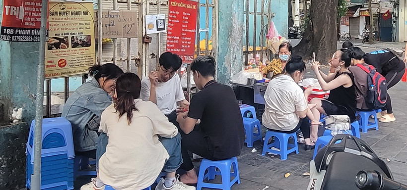 Học sinh, sinh viên hồn nhiên ngồi ăn quán xiên nướng vỉa hè quanh khu vực trường Tiểu học Lê Ngọc Hân, quận Hai Bà Trưng. (Ảnh: Phương Anh/TTXVN)