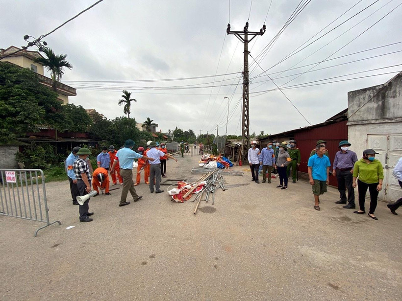 Lực lượng chức năng tháo dỡ lều bạt, băng rôn, khẩu hiệu dựng trái phép trên hành lang giao thông ở khu vực xã An Phượng. (Ảnh: Mạnh Tú/TTXVN)