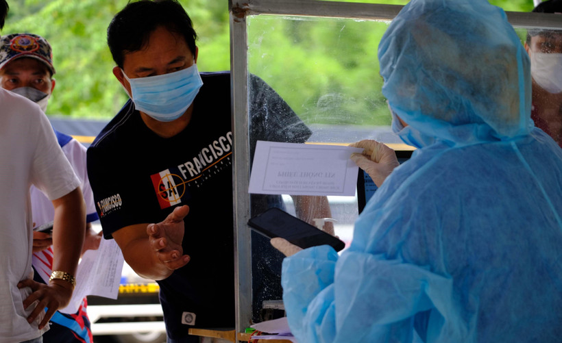 Lực lượng y tế kiểm tra lại thông tin của một tài xế tại khu vực khai báo y tế, xuất trình các giấy tờ liên qua khi đi qua trạm kiểm soát COVID-19 trên quốc lộ 20, tỉnh Lâm Đồng. (Ảnh: Nguyễn Dũng - TTXVN)