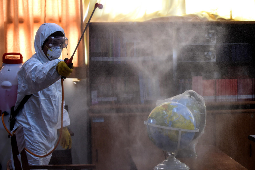 Nhân viên hội Chữ thập đỏ phun thuốc khử trùng tại trường học ở Jakarta, Indonesia, nhằm ngăn chặn sự lây lan của COVID-19. (Ảnh: THX/TTXVN)