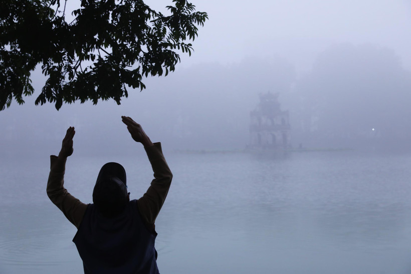 Một người đàn ông tập thể dục bên hồ Hoàn Kiếm, Hà Nội trong sương sớm. (Ảnh: Lâm Khánh/TTXVN)