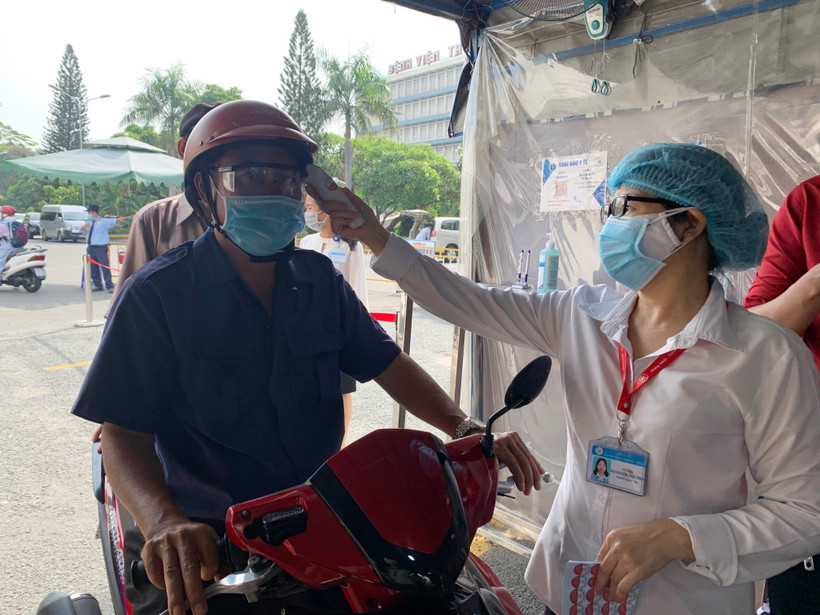 Đo thân nhiệt cho người dân đến khám bệnh tại Bệnh viện Thống Nhất Thành phố Hồ Chí Minh. (Ảnh: Đinh Hằng/TTXVN)