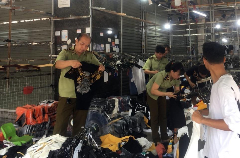 Lực lượng chức năng kiểm tra một cửa hàng kinh doanh quần áo tại chợ Ninh Hiệp. (Ảnh: TTXVN phát)