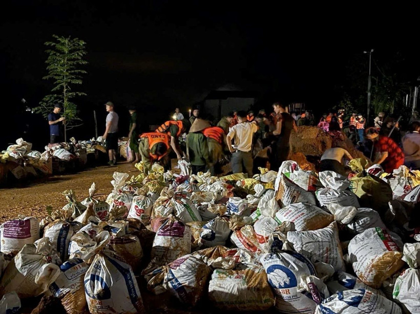 Hàng trăm người dân và các lực lượng chức năng vẫn đang khẩn trương chuyển các bao đất tới vị trí vỡ đê. (Ảnh: Quang Cường/TTXVN)