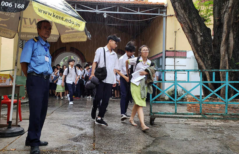 Mưa lớn khiến thí sinh gặp khó khăn khi rời khỏi điểm thi tại Hội đồng thi Trường THPT Marie Curie, Quận 3, Thành phố Hồ Chí Minh. (Ảnh: Xuân Dự/TTXVN)