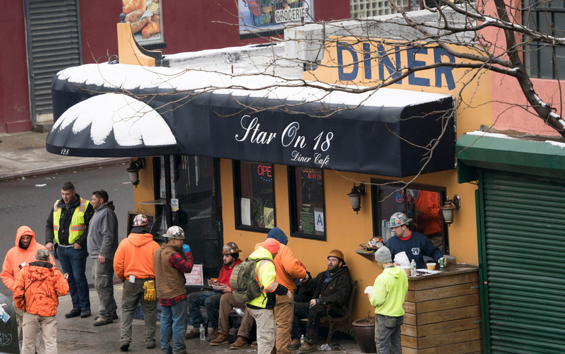 Các công nhân xây dựng trong giờ nghỉ giải lao tại một quán càphê ở New York, Mỹ. (Ảnh: AFP/TTXVN)