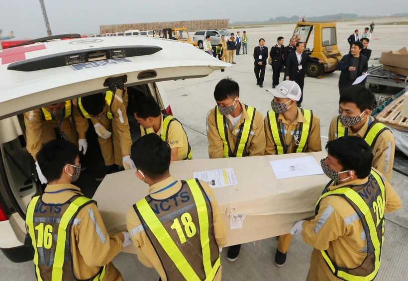Nhân viên sân bay quốc tế Nội Bài vận chuyển thi thể các nạn nhân lên ô tô để đưa về quê nhà. (Ảnh: Lâm Khánh/TTXVN)