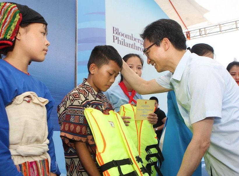 Phó Thủ tướng Chính phủ Vũ Đức Đam tặng áo phao cho các em nhỏ tại buổi lễ. (Ảnh: Thanh Tùng/TTXVN)