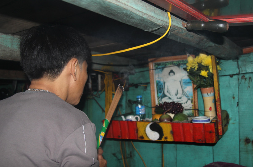 Ngư dân thực hiện nghi thức "cúng thuyền" cuối năm trong khoang lái của phương tiện. (Ảnh: Xuân Tiến/TTXVN)